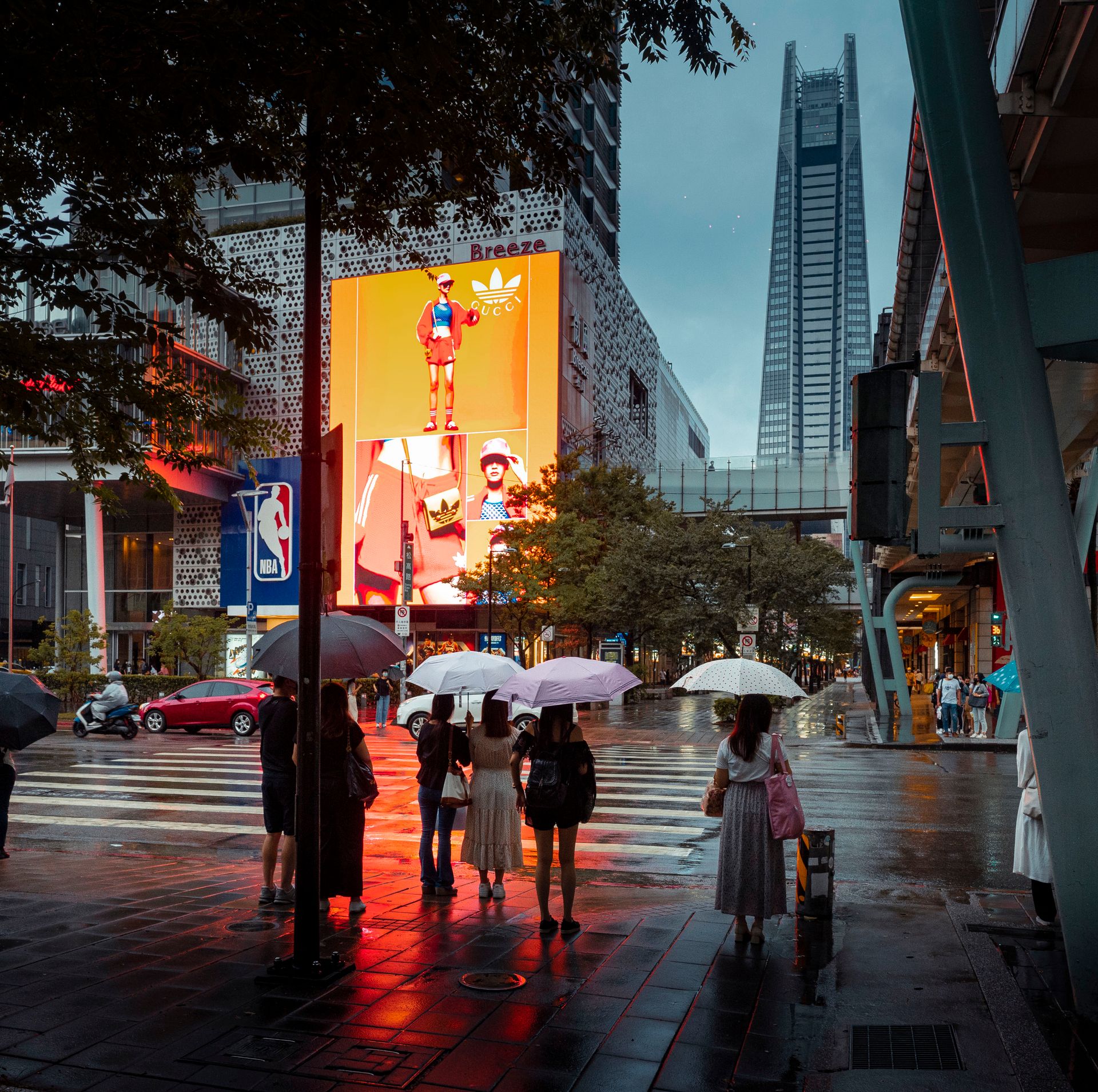 Lit signs and screens over a rainy downtown street